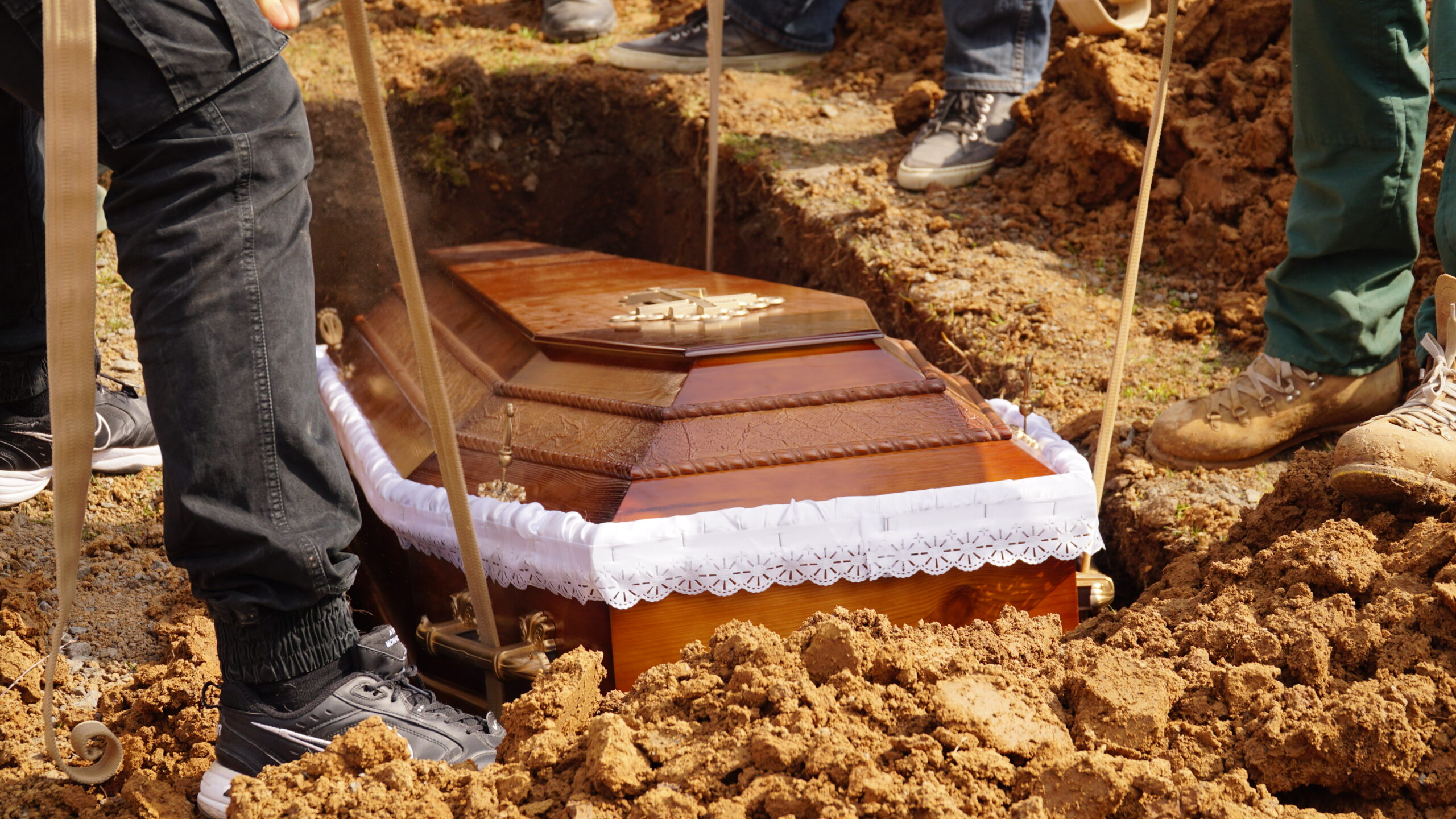 Burial. Men lower the coffin into the grave. n